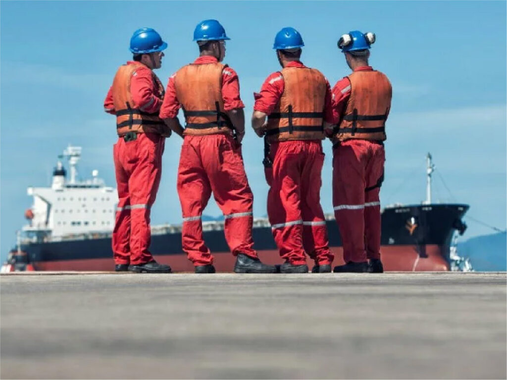 Marine port workers looking at cargo ship